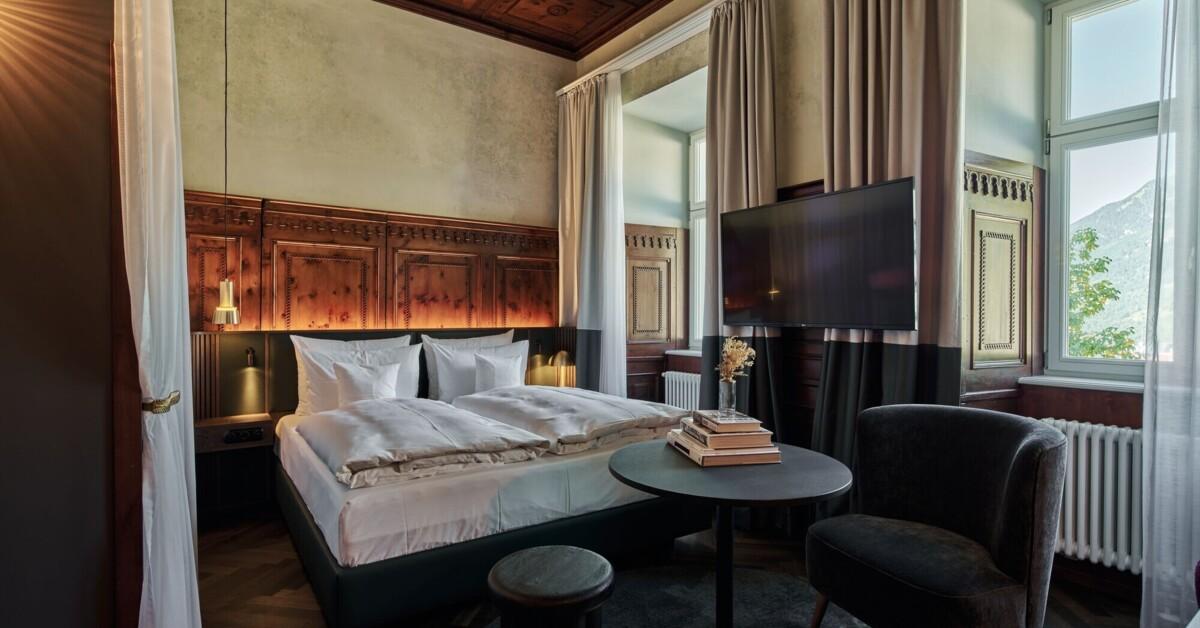 Bad Gastein hotel room — carved timber panelling, gold lamps and mountain view through tall windows