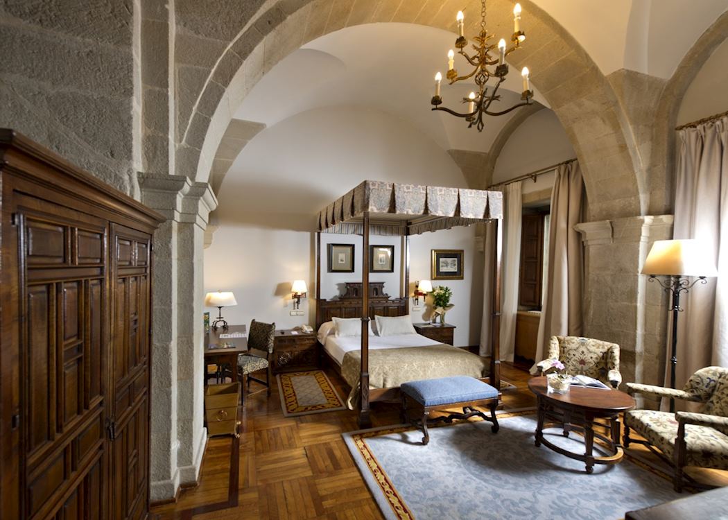 Parador de Santiago de Compostela — stone arches, four-poster bed and chandelier in the oldest hotel in the world