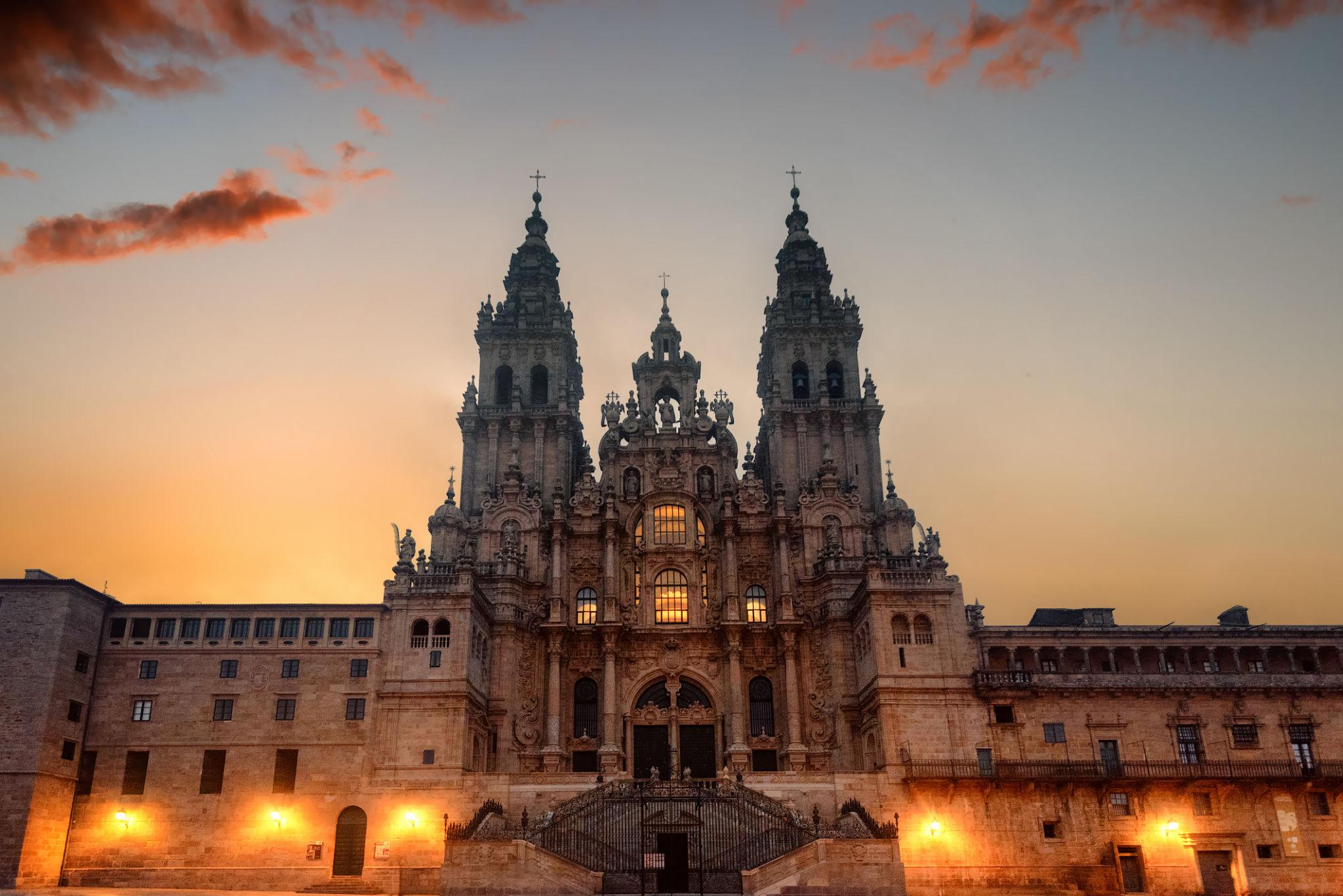 Cathedral of Santiago de Compostela at dusk — the Baroque towers lit against an orange sky