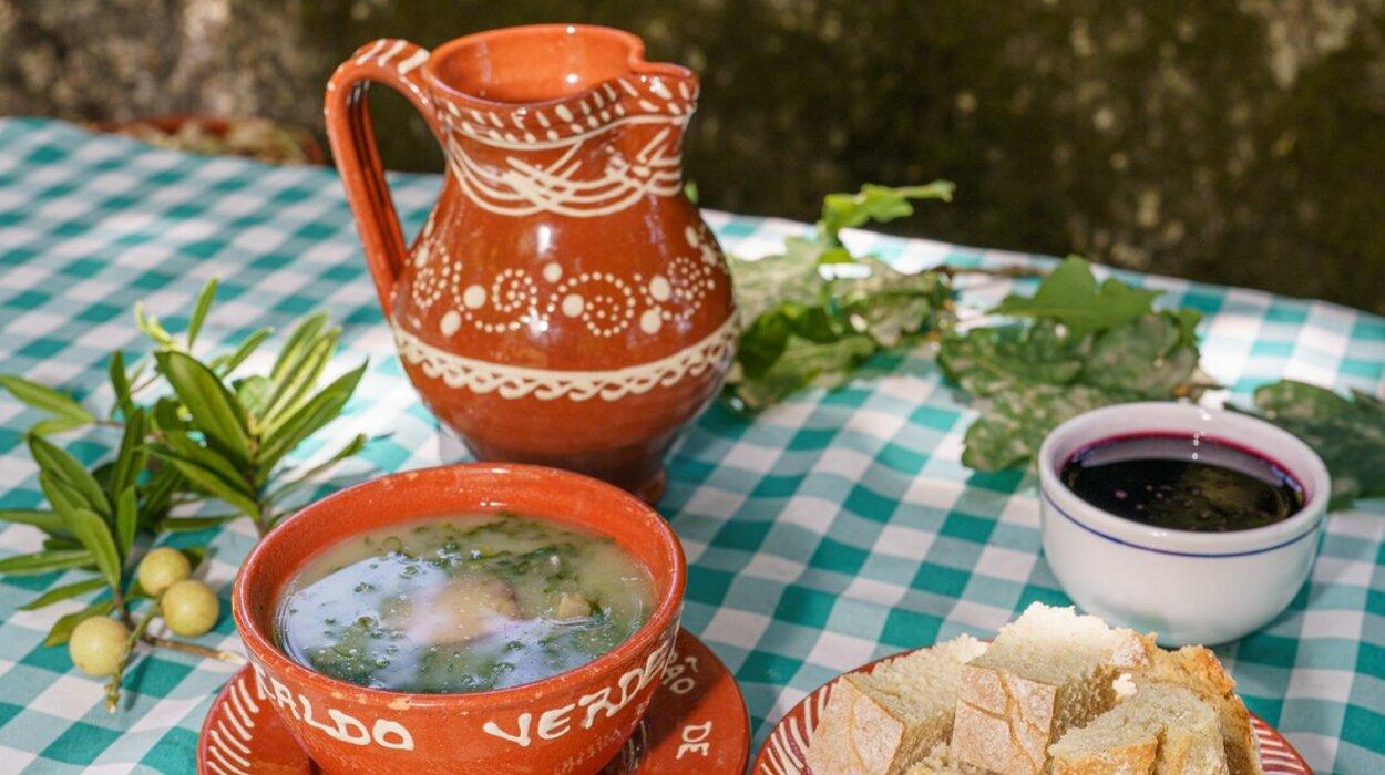 Caldo verde in terracotta bowl with decorated wine jug — the dish and the vessel that define Minho food