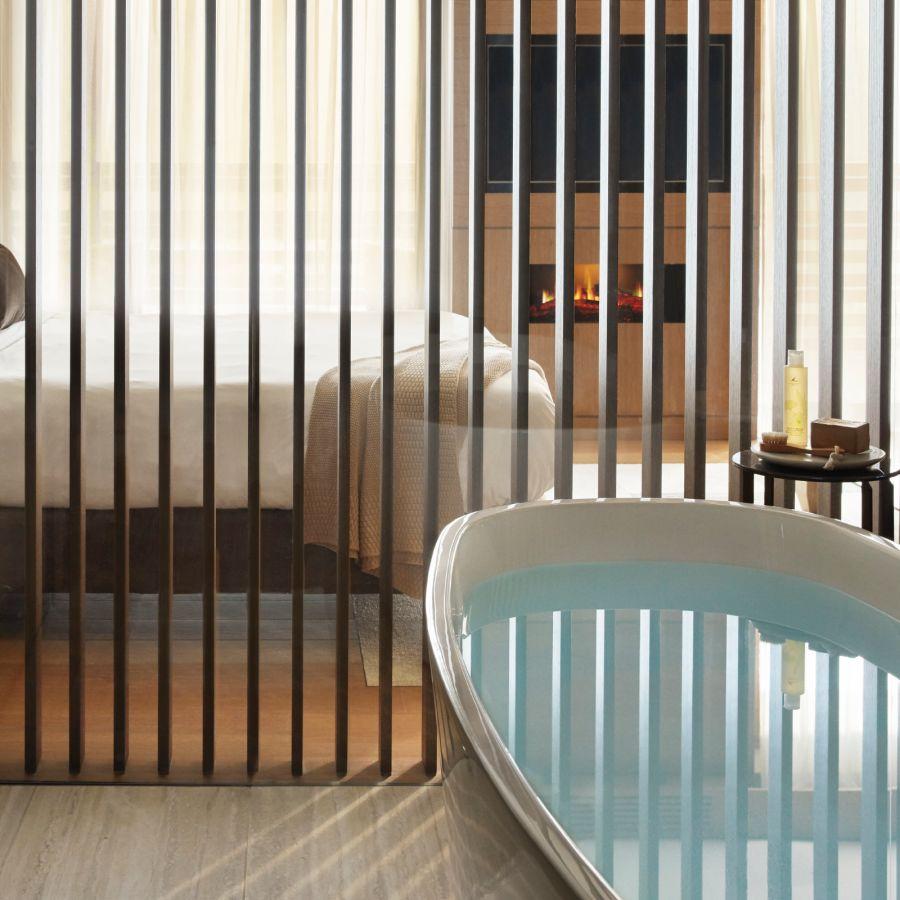 Luxury Trentino resort room — freestanding bath, slatted screen and fireplace